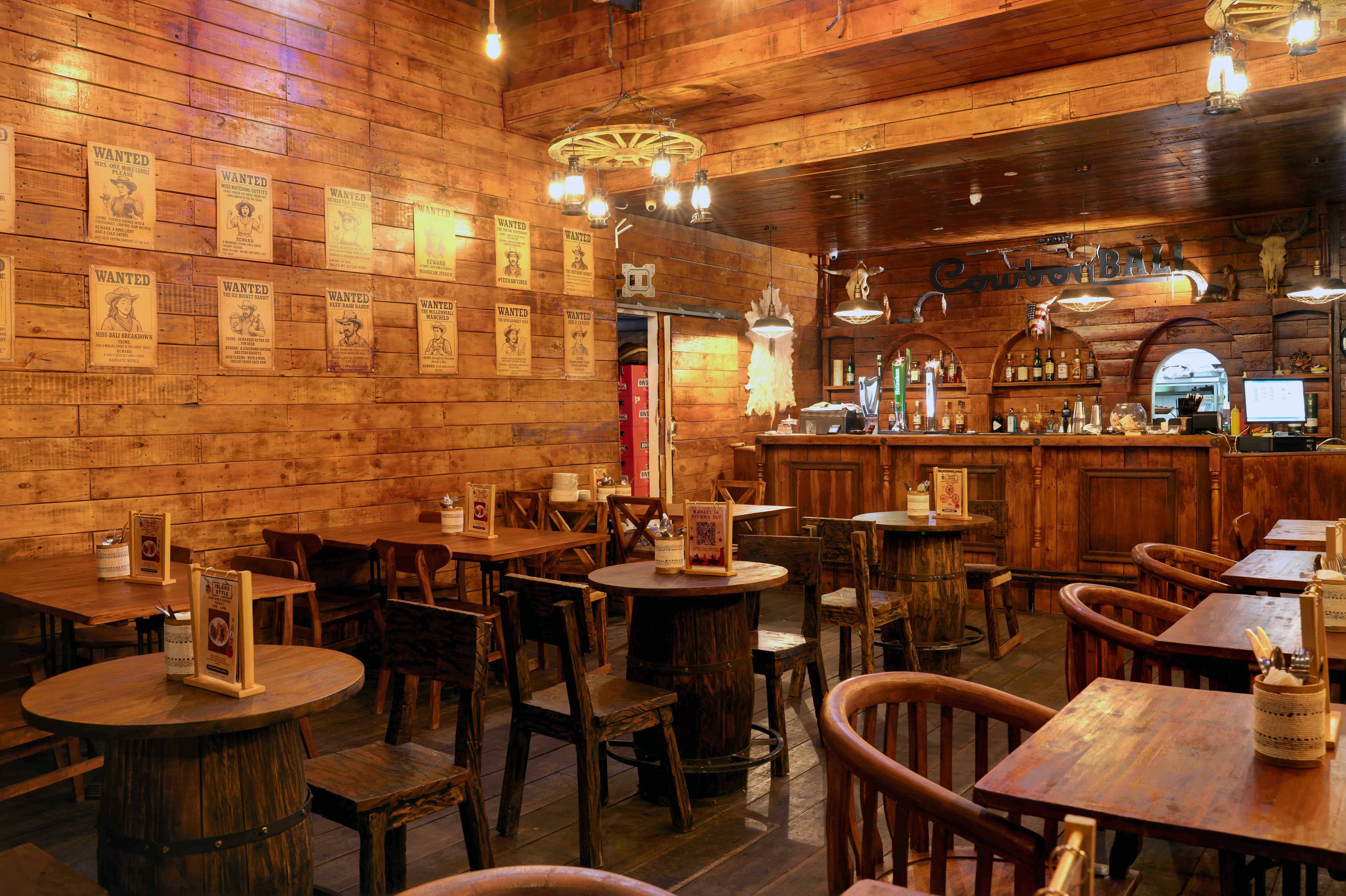 Main dining room with barrel tables and wagon wheel chandeliers